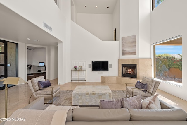 tiled living area with visible vents, a high ceiling, and a tile fireplace