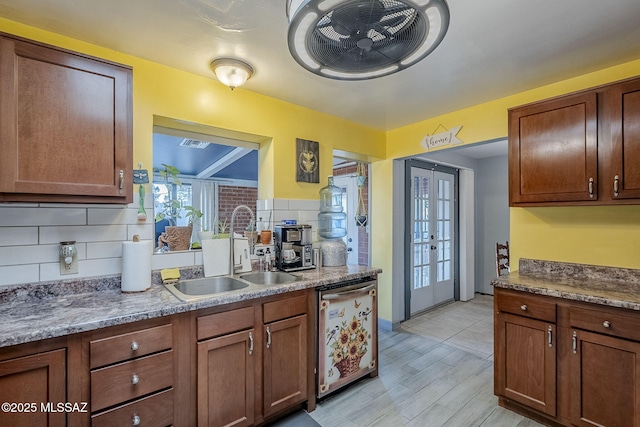 kitchen featuring french doors, light wood-type flooring, tasteful backsplash, stainless steel dishwasher, and sink