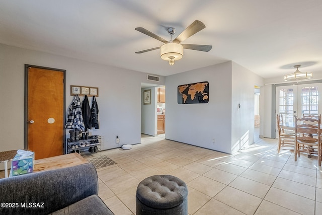 tiled living room with ceiling fan and french doors