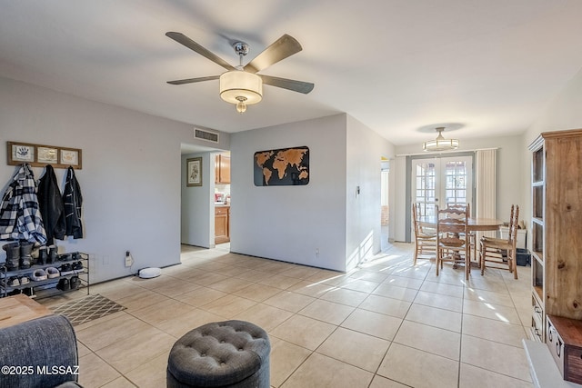 tiled living room with french doors and ceiling fan