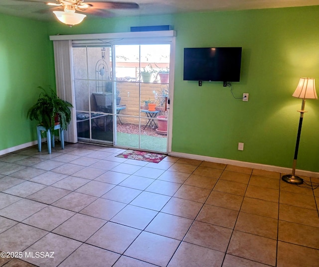 empty room with light tile patterned floors, a ceiling fan, and baseboards