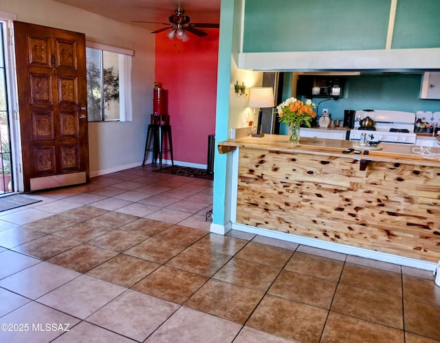 kitchen featuring tile patterned flooring, a ceiling fan, a wealth of natural light, and gas range gas stove