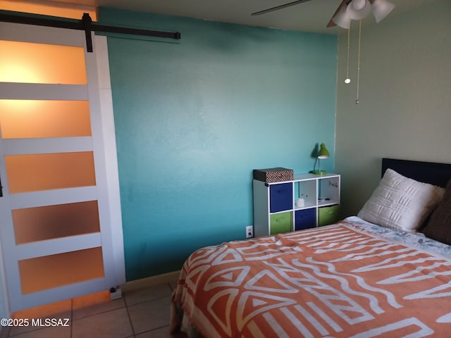 bedroom with tile patterned flooring, a ceiling fan, and a barn door