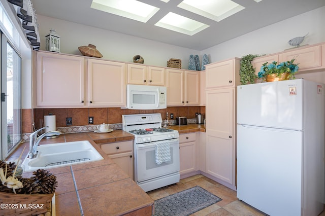 kitchen featuring backsplash, sink, white appliances, tile counters, and light tile patterned floors