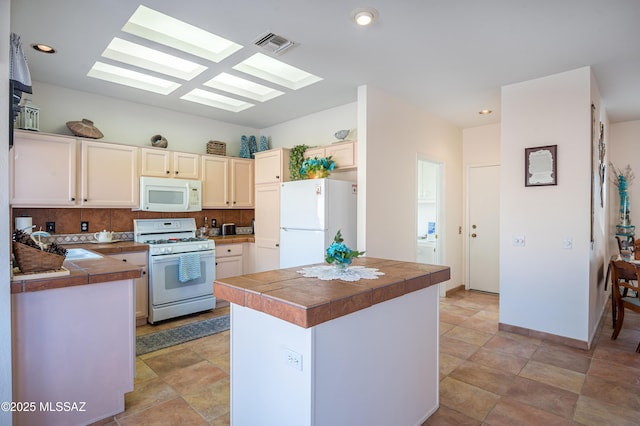 kitchen featuring kitchen peninsula, a skylight, backsplash, and white appliances