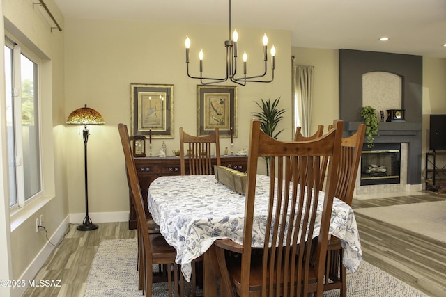 dining area with light hardwood / wood-style floors, a fireplace, and an inviting chandelier