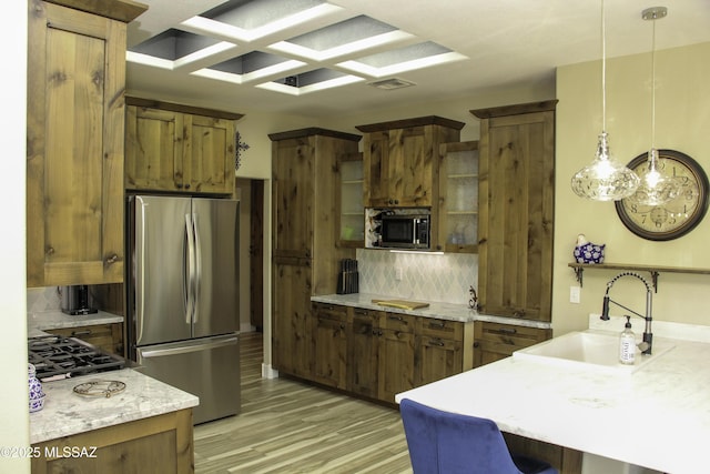 kitchen featuring sink, light hardwood / wood-style flooring, backsplash, pendant lighting, and appliances with stainless steel finishes