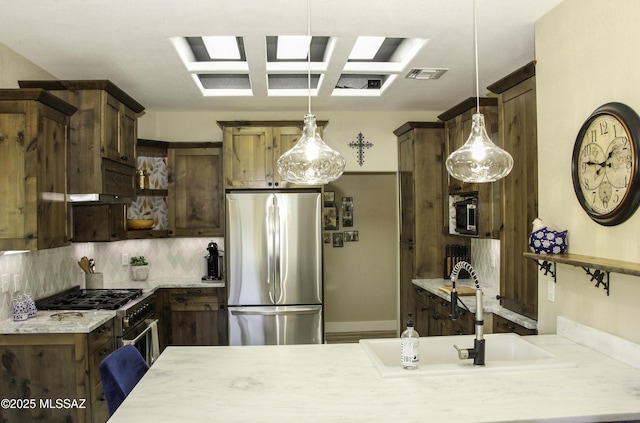 kitchen featuring appliances with stainless steel finishes, decorative light fixtures, tasteful backsplash, and sink