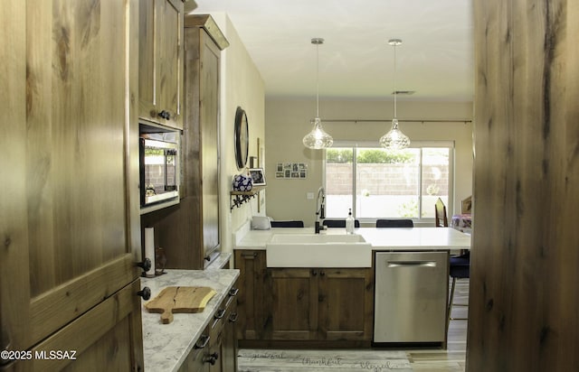 kitchen featuring light stone countertops, built in microwave, sink, dishwasher, and hanging light fixtures