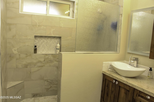 bathroom featuring tiled shower and vanity