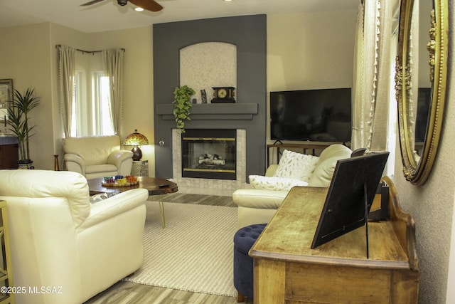 living room featuring ceiling fan and a tiled fireplace