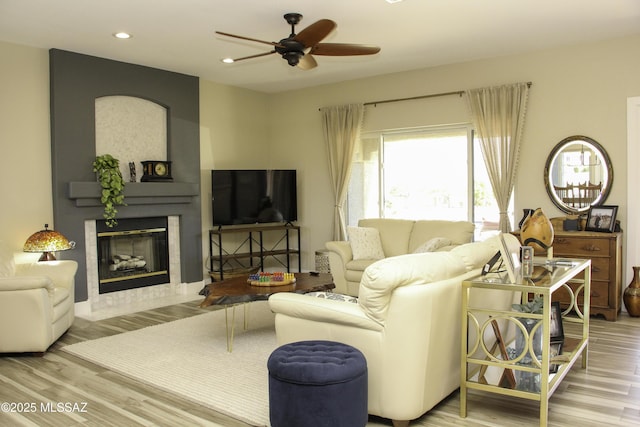 living room featuring ceiling fan, a fireplace, and wood-type flooring