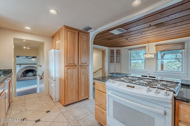 kitchen with dark stone counters, white appliances, visible vents, and light tile patterned floors