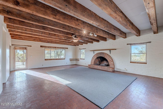 unfurnished living room featuring brick wall, beamed ceiling, a brick fireplace, and brick floor