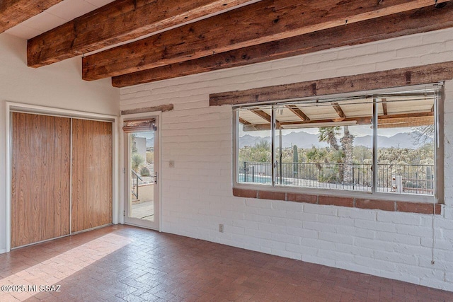 empty room with brick floor and beam ceiling