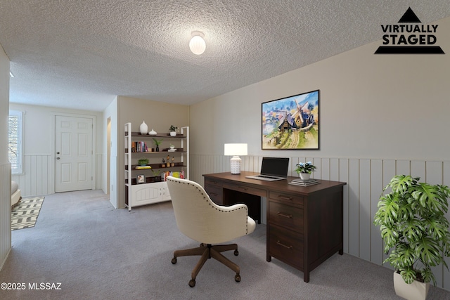 carpeted home office with a wainscoted wall and a textured ceiling