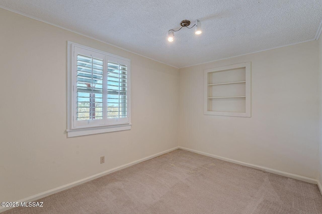 unfurnished room featuring a textured ceiling, carpet floors, built in shelves, and baseboards