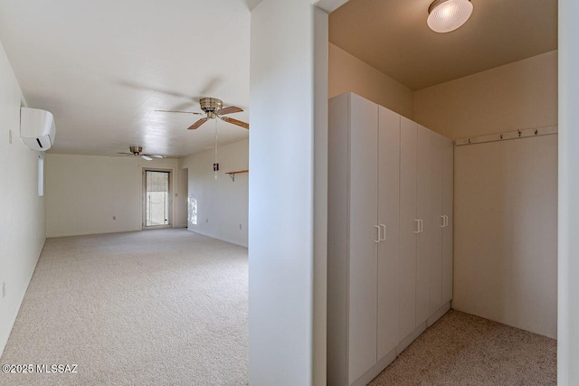 empty room featuring an AC wall unit, light colored carpet, and ceiling fan