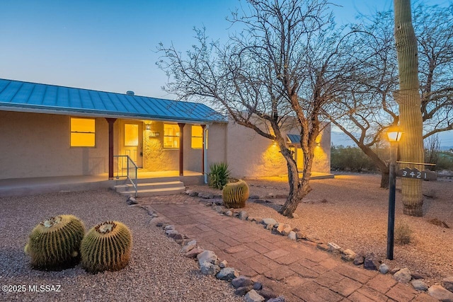 view of front of property featuring a standing seam roof, a porch, metal roof, and stucco siding