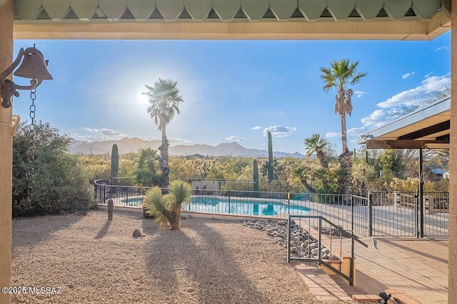 community pool with a patio area, a mountain view, and fence