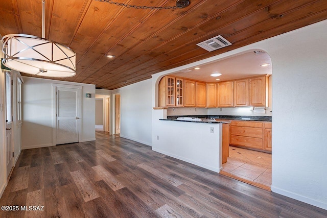 kitchen featuring dark wood-style flooring, glass insert cabinets, dark countertops, and visible vents