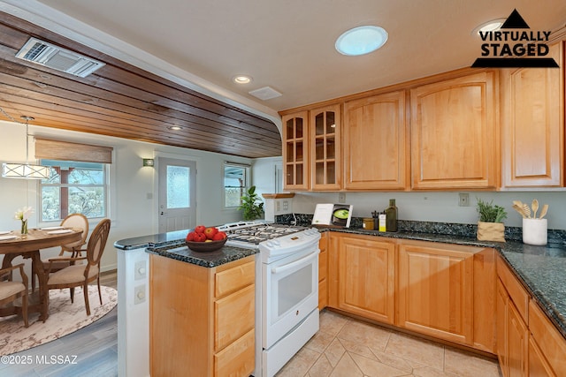 kitchen with white range with gas stovetop, glass insert cabinets, dark stone countertops, a peninsula, and recessed lighting