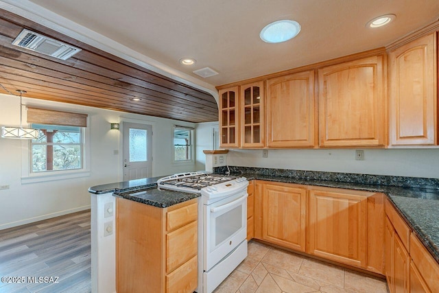 kitchen featuring visible vents, dark stone counters, glass insert cabinets, a peninsula, and white gas range