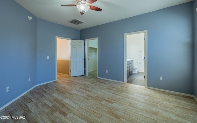 unfurnished bedroom featuring a walk in closet, connected bathroom, light hardwood / wood-style floors, and ceiling fan