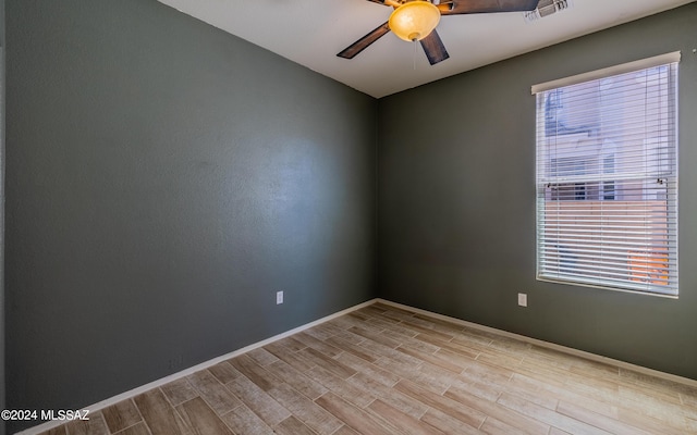 empty room featuring a wealth of natural light, ceiling fan, and light hardwood / wood-style flooring