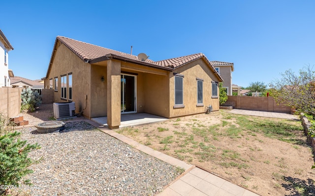 back of house featuring cooling unit, a patio, and a fire pit