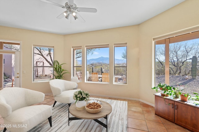 living area featuring a mountain view, light tile patterned floors, a wealth of natural light, and ceiling fan