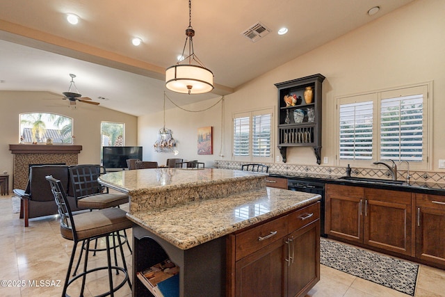 kitchen featuring lofted ceiling, ceiling fan, tasteful backsplash, a kitchen island, and light stone counters