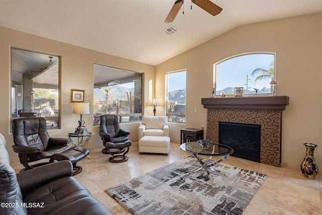 living room with a tile fireplace, tile patterned flooring, vaulted ceiling, and ceiling fan