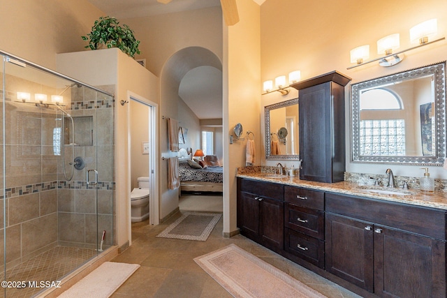 bathroom with vanity, vaulted ceiling, tile patterned flooring, toilet, and walk in shower