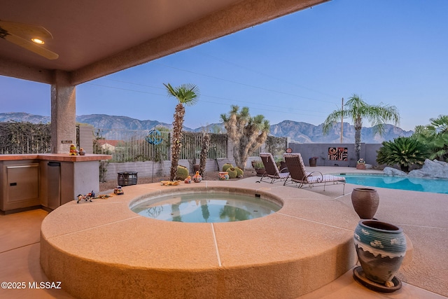 view of swimming pool with a mountain view and an in ground hot tub