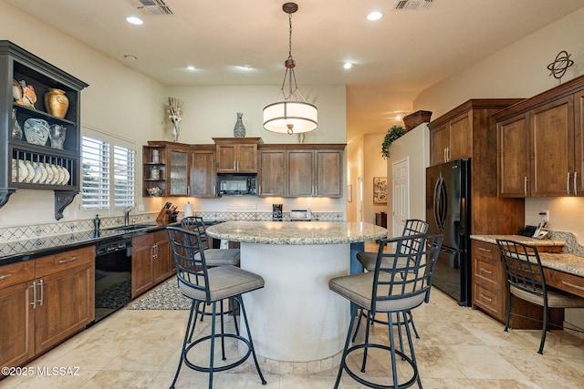 kitchen with light stone countertops, sink, backsplash, decorative light fixtures, and black appliances