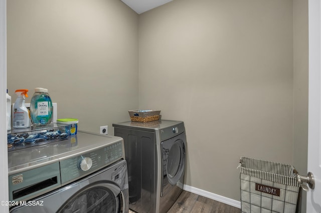 clothes washing area featuring washer and clothes dryer and dark wood-type flooring