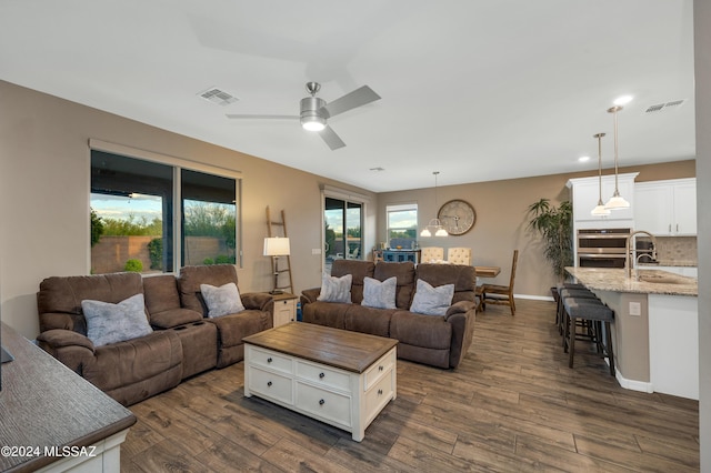 living room with ceiling fan, sink, and dark wood-type flooring