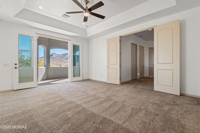 interior space with a raised ceiling, access to exterior, french doors, and carpet floors