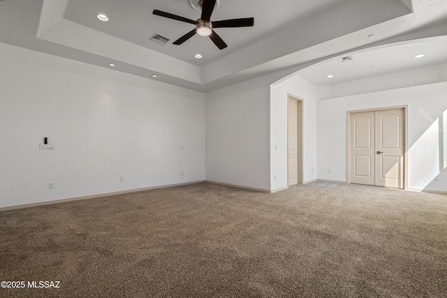 carpeted empty room with a tray ceiling and ceiling fan