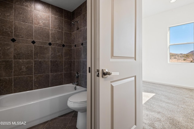 bathroom with tile patterned flooring, toilet, and tiled shower / bath