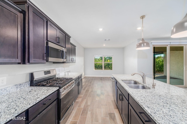 kitchen featuring appliances with stainless steel finishes, light stone counters, hanging light fixtures, and sink