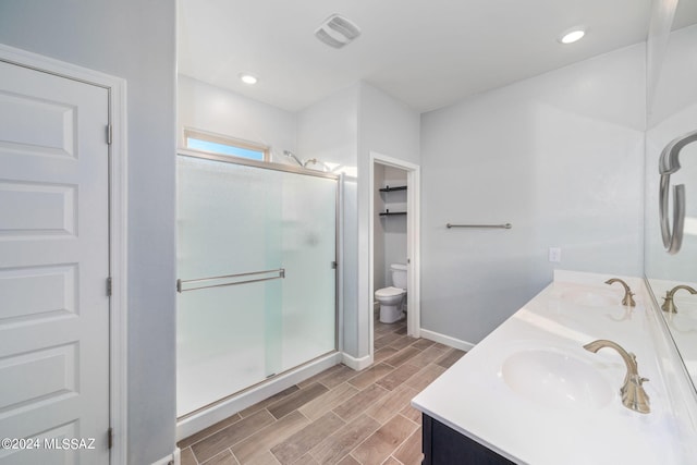 bathroom with a shower with door, vanity, and toilet