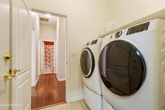 laundry room with washing machine and dryer and light hardwood / wood-style floors