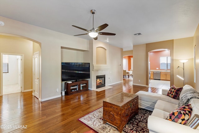 living room with hardwood / wood-style floors, a tile fireplace, and ceiling fan