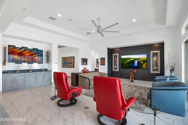 home theater room featuring a raised ceiling and ceiling fan