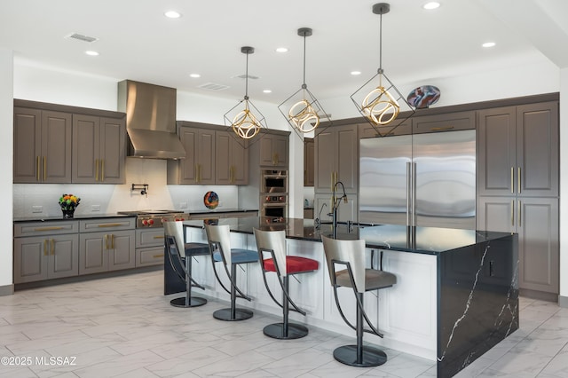 kitchen with a kitchen island with sink, wall chimney range hood, appliances with stainless steel finishes, and sink