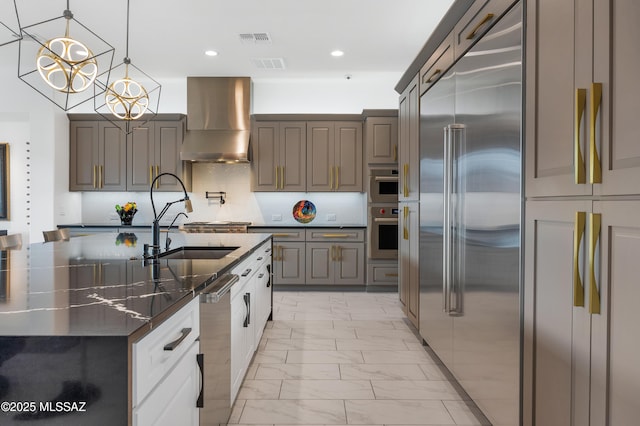 kitchen with stainless steel appliances, sink, tasteful backsplash, hanging light fixtures, and wall chimney range hood