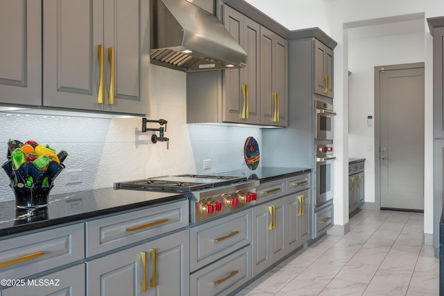 kitchen featuring gray cabinets, backsplash, and wall chimney exhaust hood