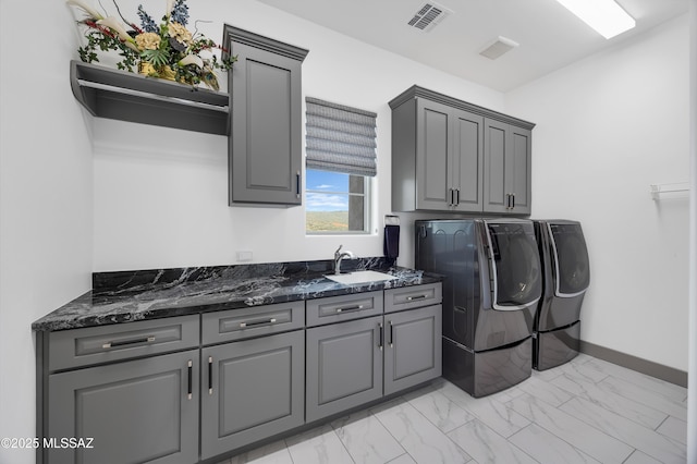 clothes washing area with sink, washer and clothes dryer, and cabinets